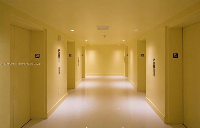 hallway with elevator, visible vents, recessed lighting, and baseboards