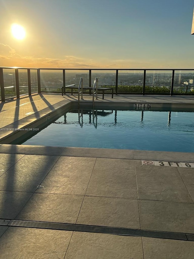 pool at dusk featuring a community pool