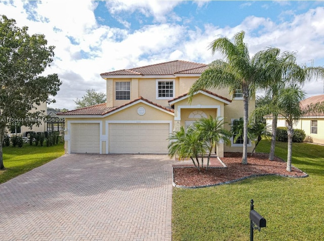 mediterranean / spanish-style home featuring decorative driveway, a tile roof, stucco siding, an attached garage, and a front yard