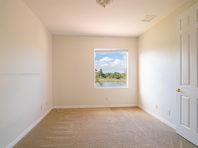 empty room featuring light carpet, visible vents, and baseboards