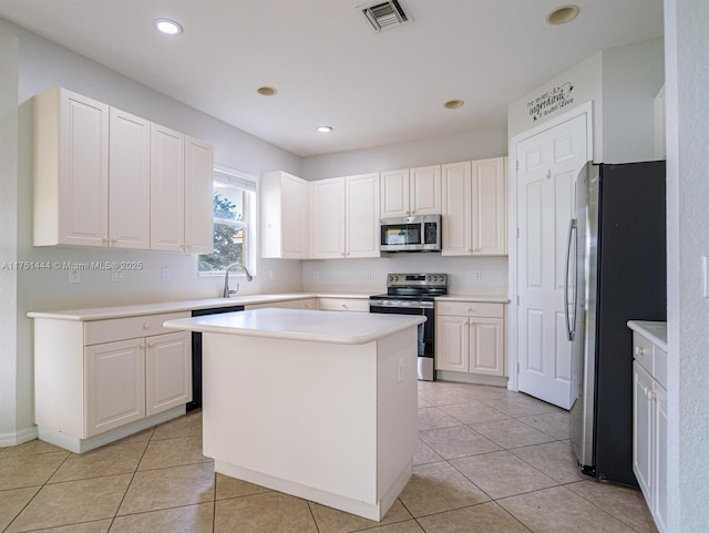 kitchen with a kitchen island, visible vents, white cabinets, light countertops, and appliances with stainless steel finishes