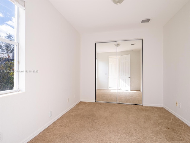 unfurnished bedroom with baseboards, carpet, visible vents, and a closet