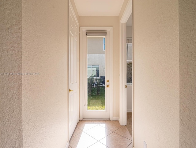 doorway to outside featuring light tile patterned floors and a textured wall