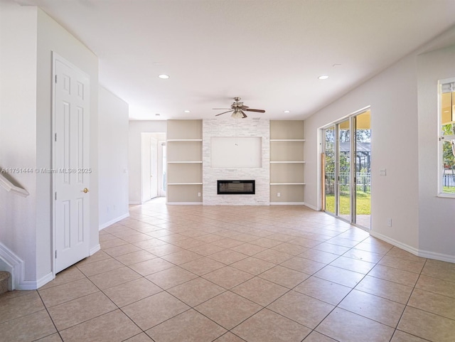 unfurnished living room with built in shelves, light tile patterned flooring, a fireplace, a ceiling fan, and baseboards