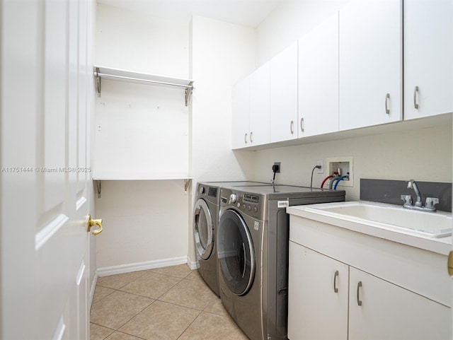 clothes washing area with cabinet space, light tile patterned flooring, a sink, washer and dryer, and baseboards