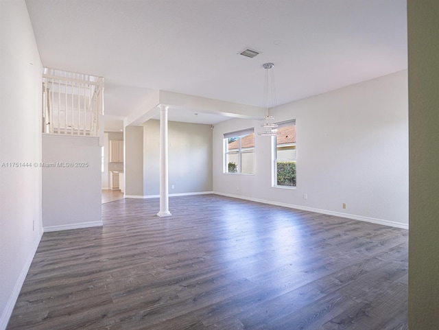 spare room with ornate columns, baseboards, visible vents, and dark wood-type flooring