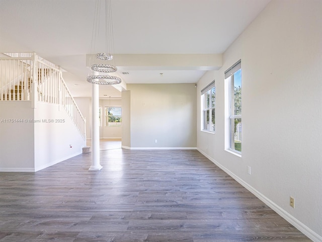 empty room with stairs, dark wood finished floors, visible vents, and baseboards