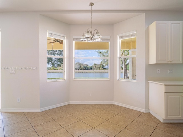 unfurnished dining area with a wealth of natural light, baseboards, and light tile patterned floors