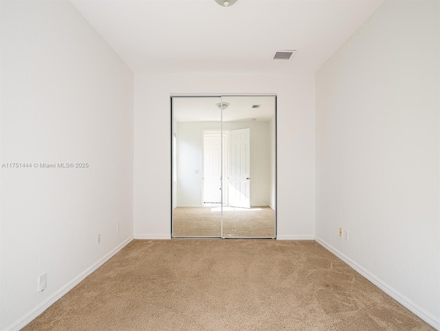 unfurnished bedroom with carpet floors, a closet, visible vents, and baseboards