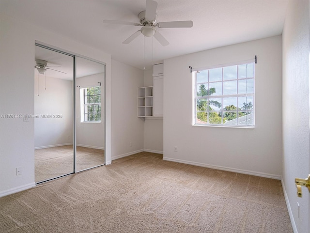 unfurnished bedroom featuring carpet, a closet, ceiling fan, and baseboards