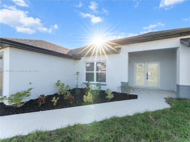 view of property exterior with a garage, french doors, and stucco siding