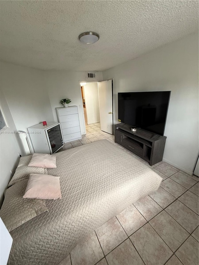 living area featuring a textured ceiling, light tile patterned floors, and visible vents