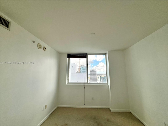 spare room featuring visible vents, light carpet, and baseboards
