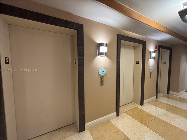 hallway with baseboards and elevator