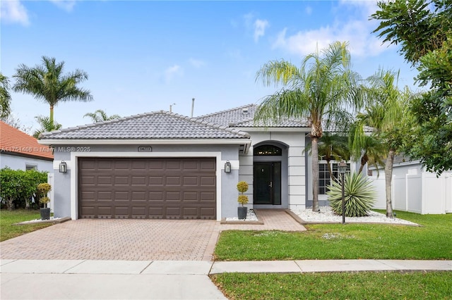 ranch-style home featuring a garage, a tiled roof, decorative driveway, and stucco siding