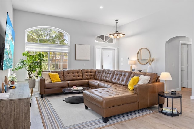 living area featuring arched walkways, recessed lighting, light wood-style flooring, and a notable chandelier