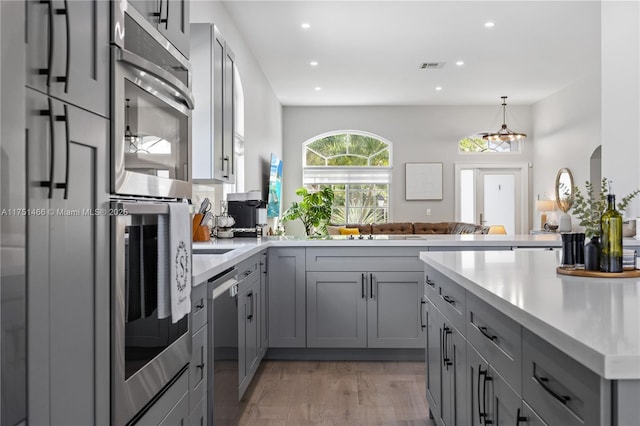 kitchen featuring gray cabinetry, visible vents, open floor plan, light countertops, and appliances with stainless steel finishes