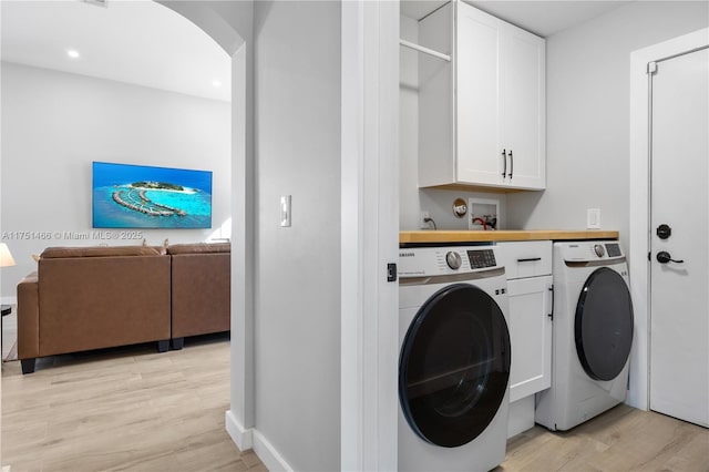 laundry area with cabinet space, arched walkways, light wood-style flooring, washer and dryer, and recessed lighting