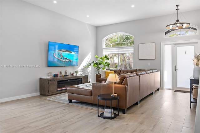 living area with baseboards, recessed lighting, a glass covered fireplace, and light wood-style floors