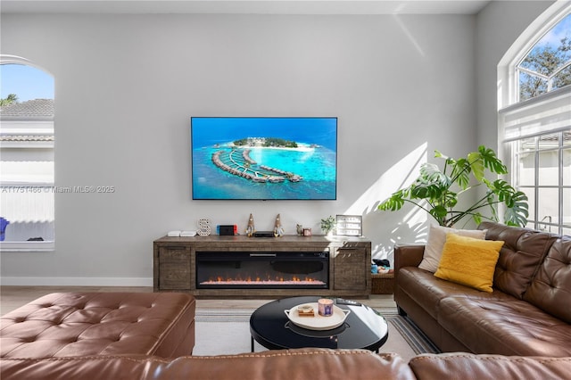 living area featuring a glass covered fireplace and baseboards