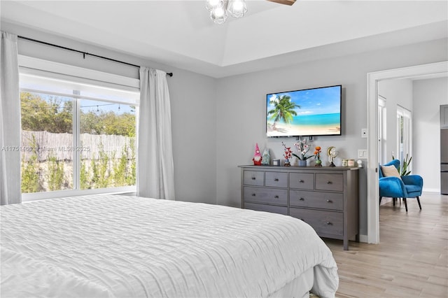 bedroom with lofted ceiling, light wood-type flooring, and baseboards