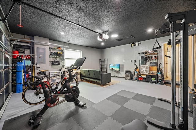 workout area with a garage, electric panel, and a textured ceiling