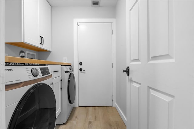 clothes washing area with cabinet space, visible vents, light wood finished floors, and separate washer and dryer