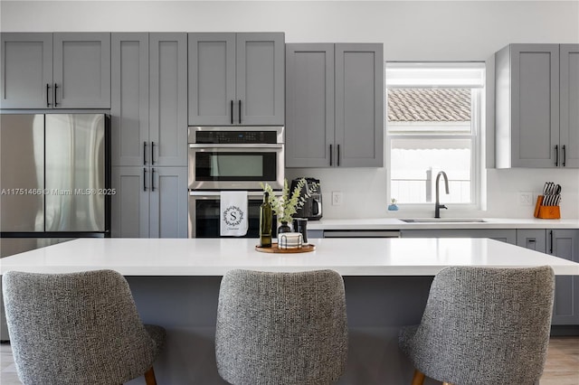 kitchen featuring gray cabinets, light countertops, a sink, and a center island