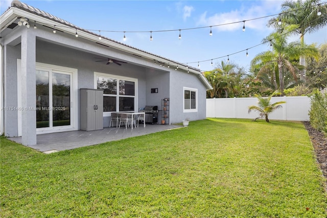 rear view of house featuring stucco siding, a fenced backyard, a yard, and a patio