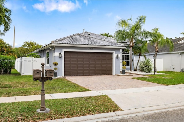 single story home featuring decorative driveway, a tile roof, stucco siding, a front yard, and a garage