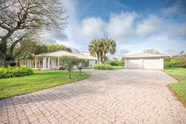 single story home featuring a detached garage and a front lawn