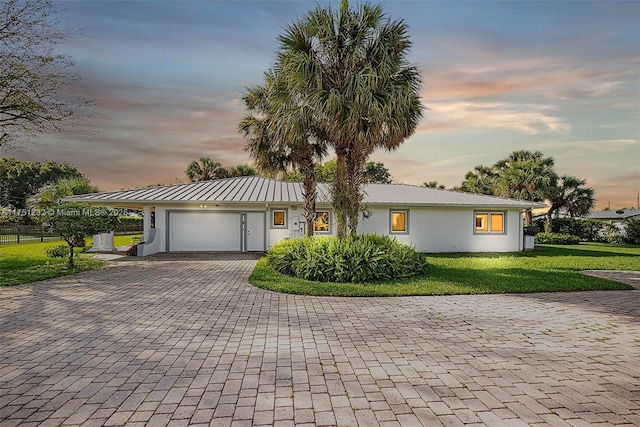 single story home featuring stucco siding, metal roof, an attached garage, decorative driveway, and a front yard