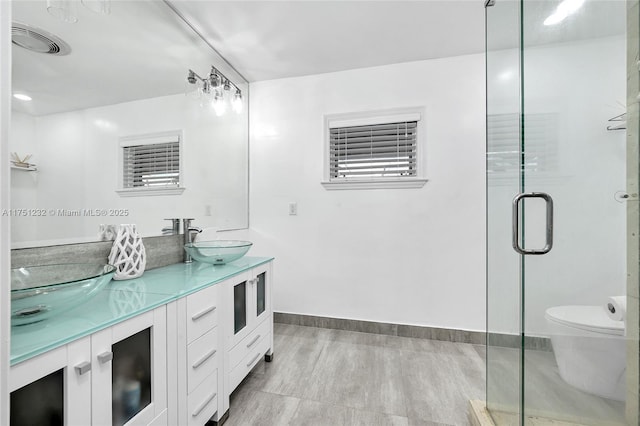 bathroom with double vanity, visible vents, toilet, a shower stall, and a sink
