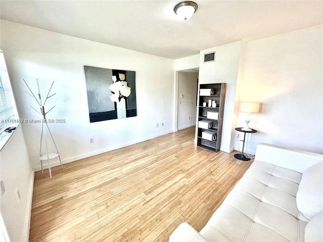 living room featuring visible vents, baseboards, and wood finished floors