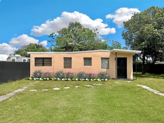 view of front of home with fence, a front lawn, and stucco siding