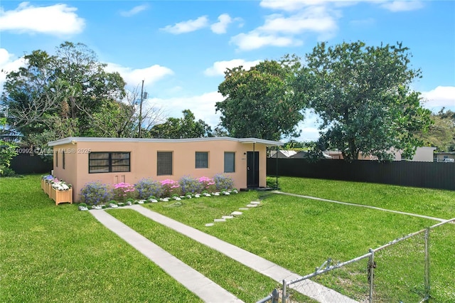 view of front of home featuring a front yard, fence private yard, and stucco siding