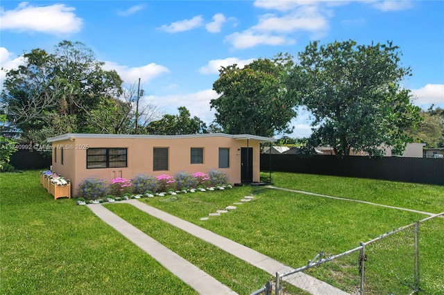 view of front of home with fence private yard, a front lawn, and stucco siding