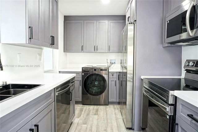 laundry area featuring washer / clothes dryer and light wood finished floors