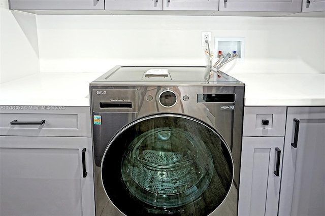 clothes washing area with washer / clothes dryer and cabinet space