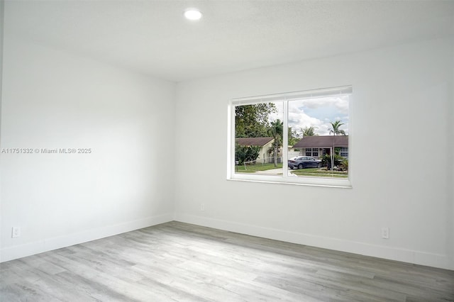 unfurnished room featuring wood finished floors, baseboards, and recessed lighting