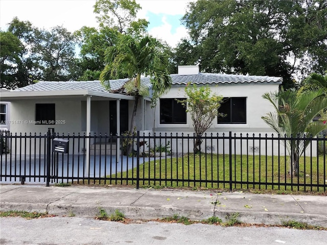 view of front facade with a fenced front yard, a front yard, a tile roof, and stucco siding