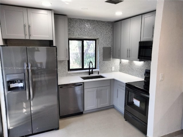 kitchen with black appliances, tasteful backsplash, a sink, and gray cabinetry