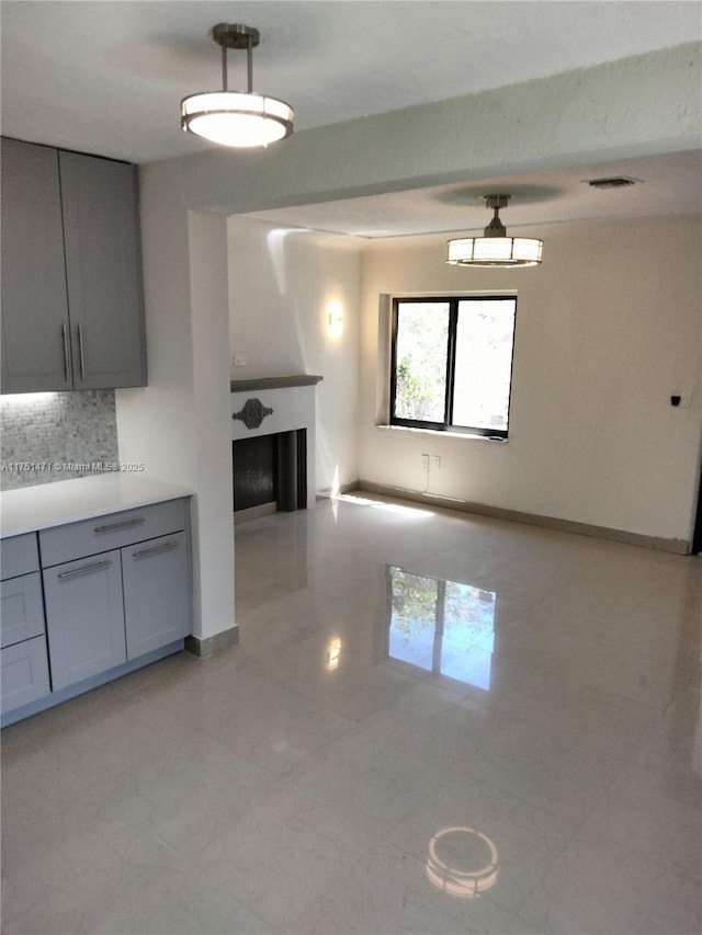 kitchen featuring a fireplace, gray cabinets, visible vents, decorative backsplash, and baseboards