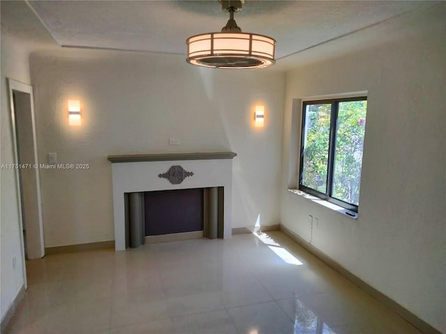 unfurnished living room featuring a fireplace and baseboards