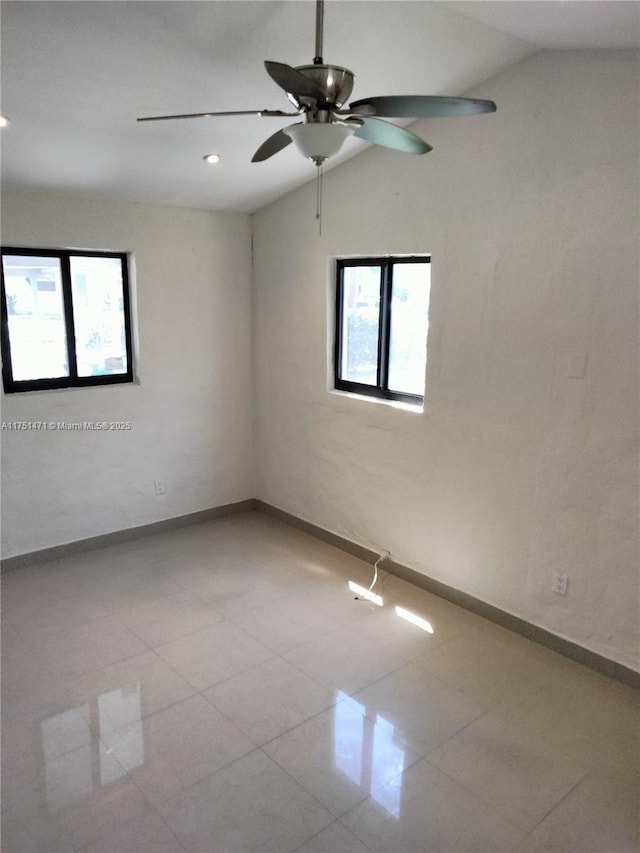 tiled spare room with vaulted ceiling, baseboards, and a healthy amount of sunlight