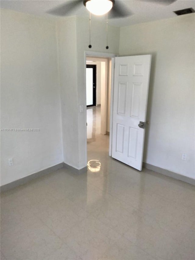 spare room featuring a ceiling fan, visible vents, and baseboards