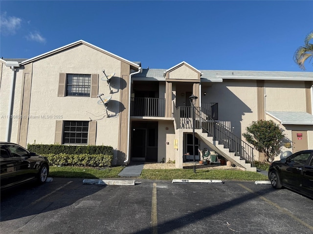 view of property featuring stairs and uncovered parking