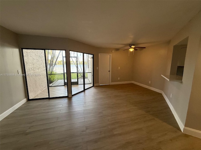 empty room featuring dark wood-style floors, a ceiling fan, and baseboards