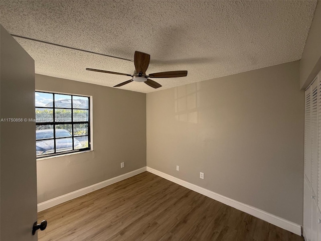 unfurnished room featuring a textured ceiling, ceiling fan, wood finished floors, and baseboards