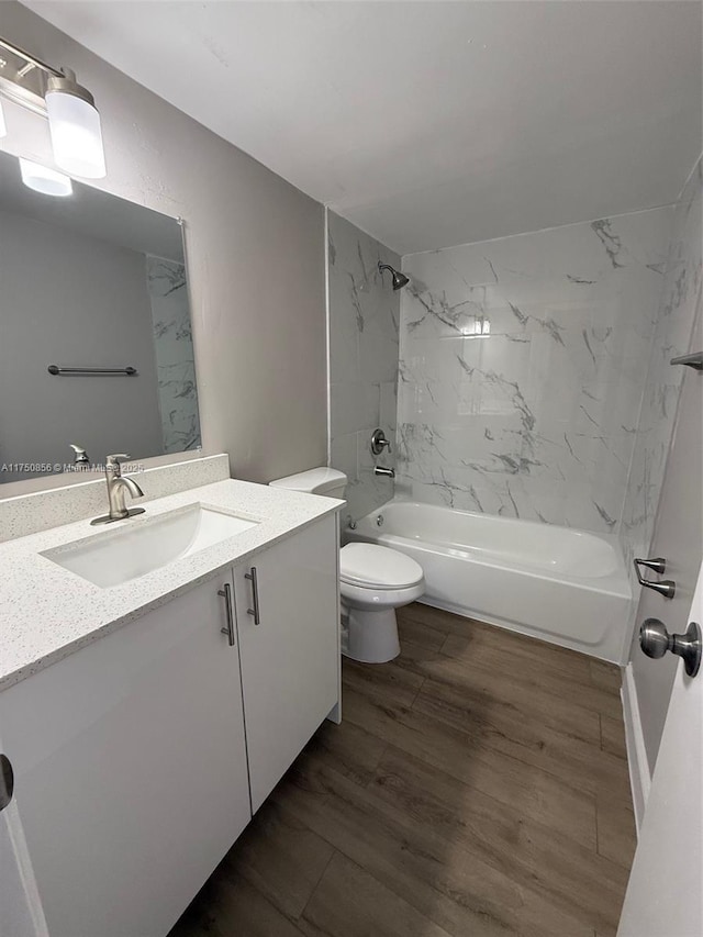 bathroom with washtub / shower combination, vanity, toilet, and wood finished floors